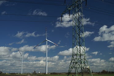 Zdjęcie słupów energetycznych i elektrowni wiatrowej na tle błękitnego nieba